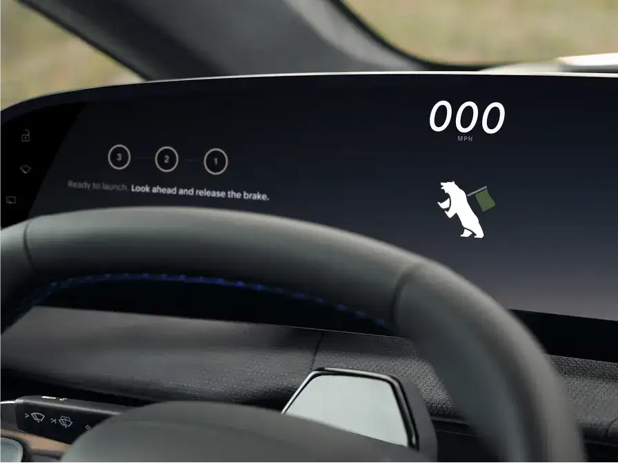 Car dashboard display showing 000 MPH speedometer, a bear icon, and launch mode prompt to release the brake.