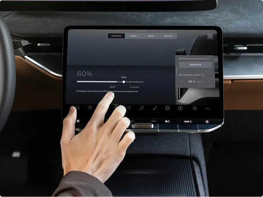 Hand adjusting electric vehicle charging settings on dashboard touchscreen showing 60% battery level and charging schedule options.