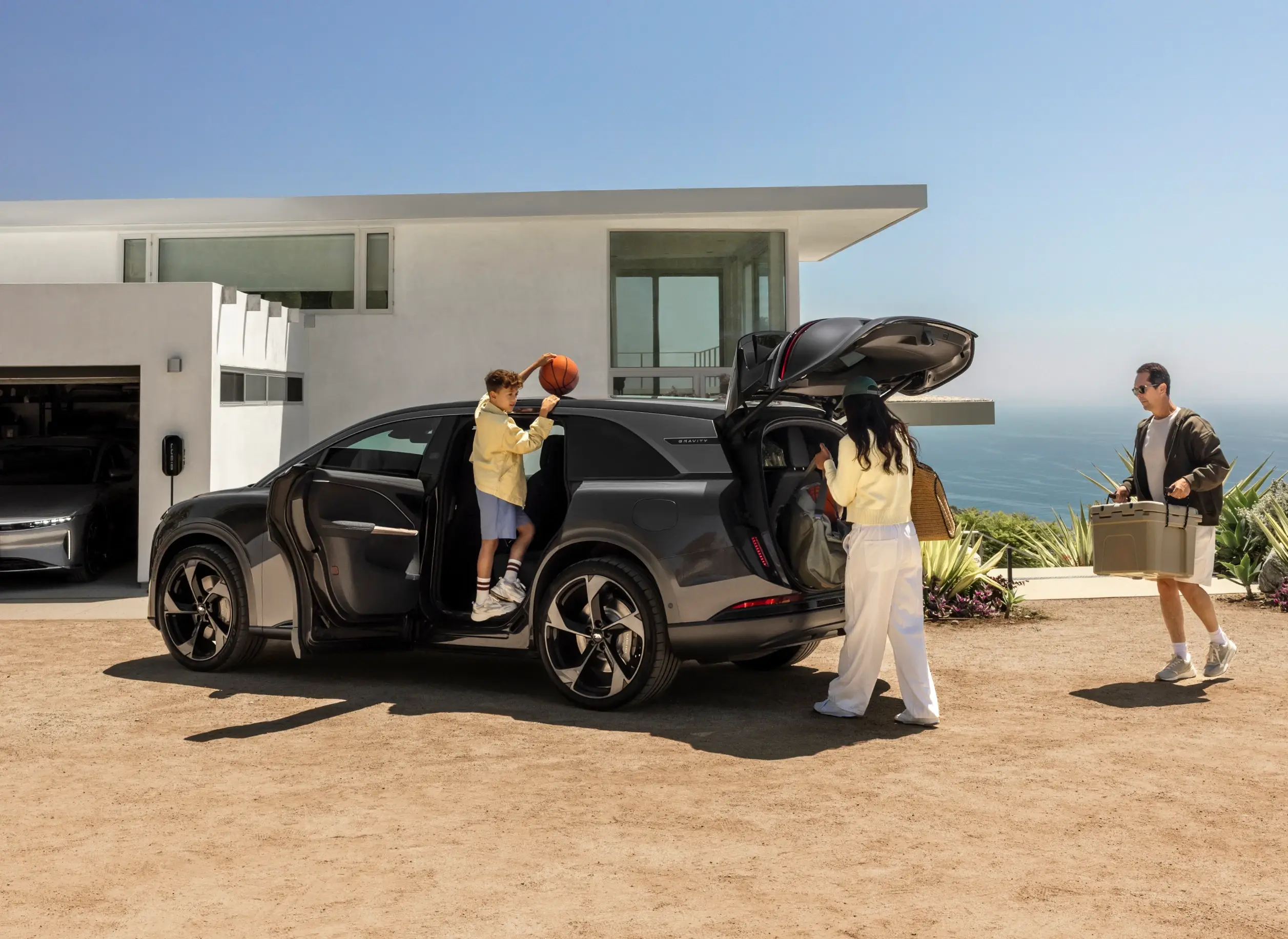Zwei Personen interagieren im Innenraum einer Lucid Gravity mit umgeklappten Rücksitzen, während Basketbälle und eine Kühlbox im hinteren Bereich liegen.