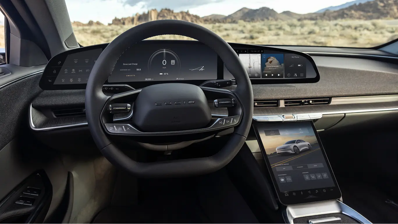 Lucid electric car interior showing a black steering wheel, wide digital dashboard display, and center touchscreen.