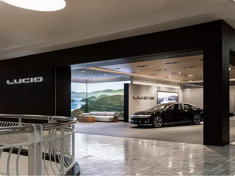 A sleek black Lucid electric sedan displayed inside a modern Lucid Motors showroom with dark walls and bright lighting.