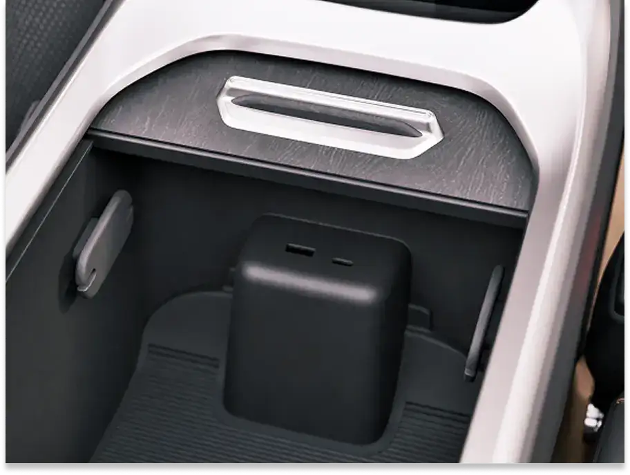 Modern car center console storage compartment with black interior and silver trim, containing a small black device.