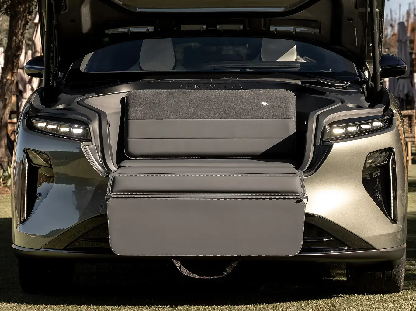 Front view of a Lucid Gravity electric vehicle with open trunk showing seating area and modern LED headlights.