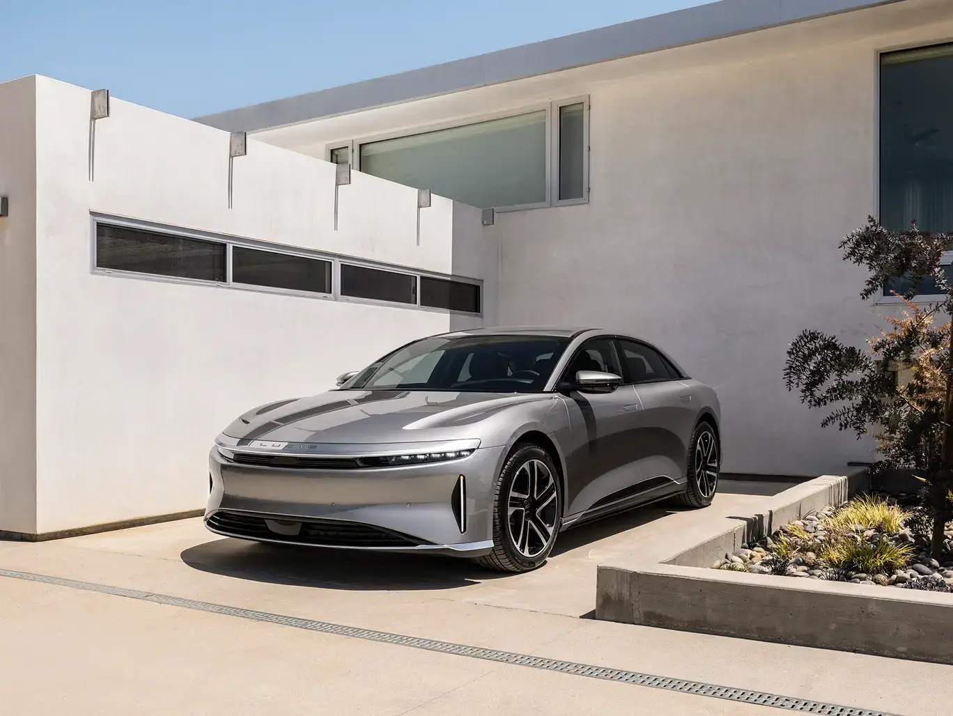 Lucid Air stationnée dans un paysage désertique avec des montagnes et un ciel nuageux en arrière-plan.