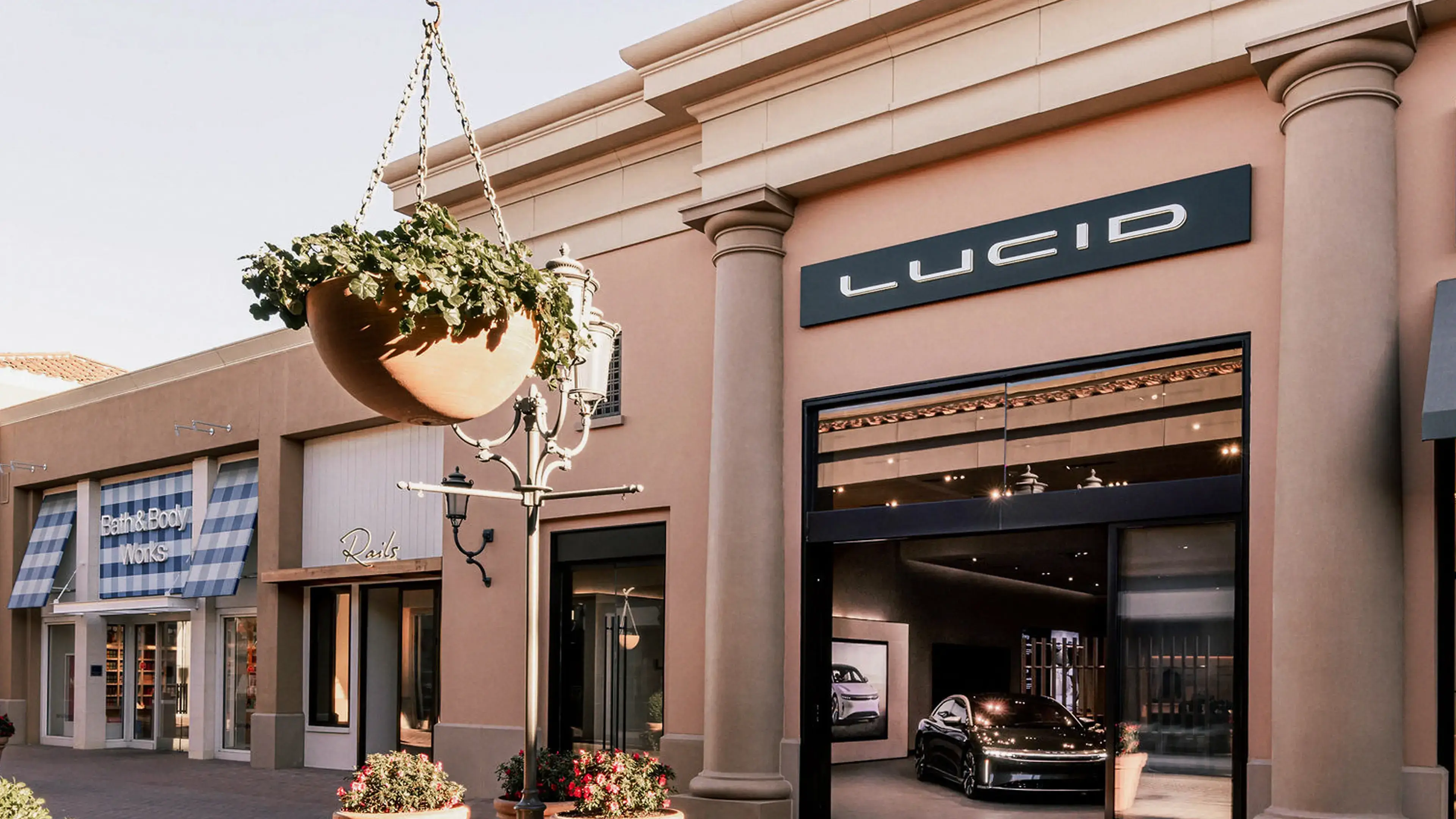 Lucid Motors showroom with elegant peach-colored facade and black electric vehicle displayed inside.