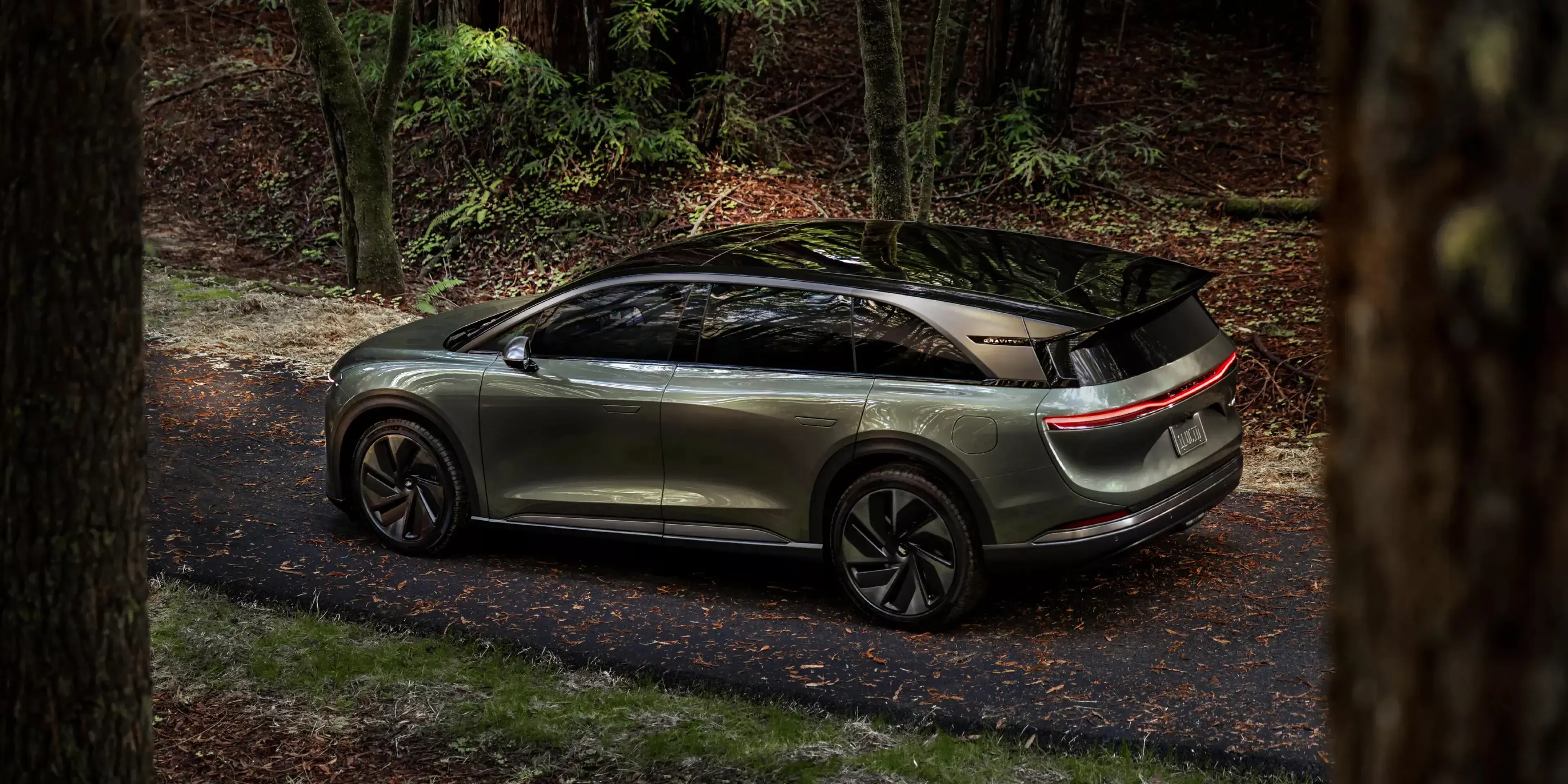 سيارة Lucid Gravity بلون أخضر أورورا وسط الطبيعة الخضراء.