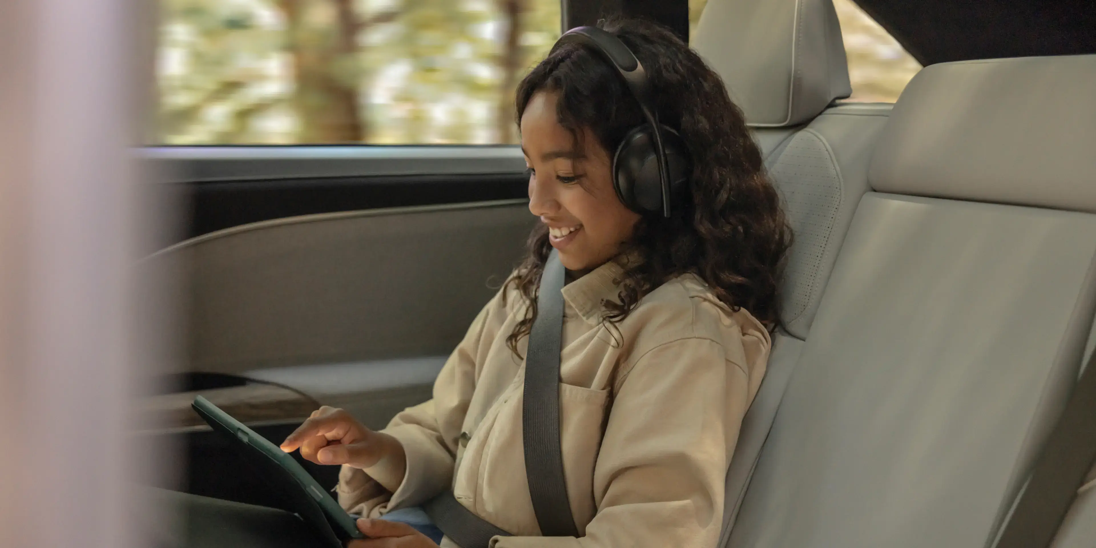 A kid sitting in the second row buckled in a seat and looking out the window while the Lucid Gravity is moving.