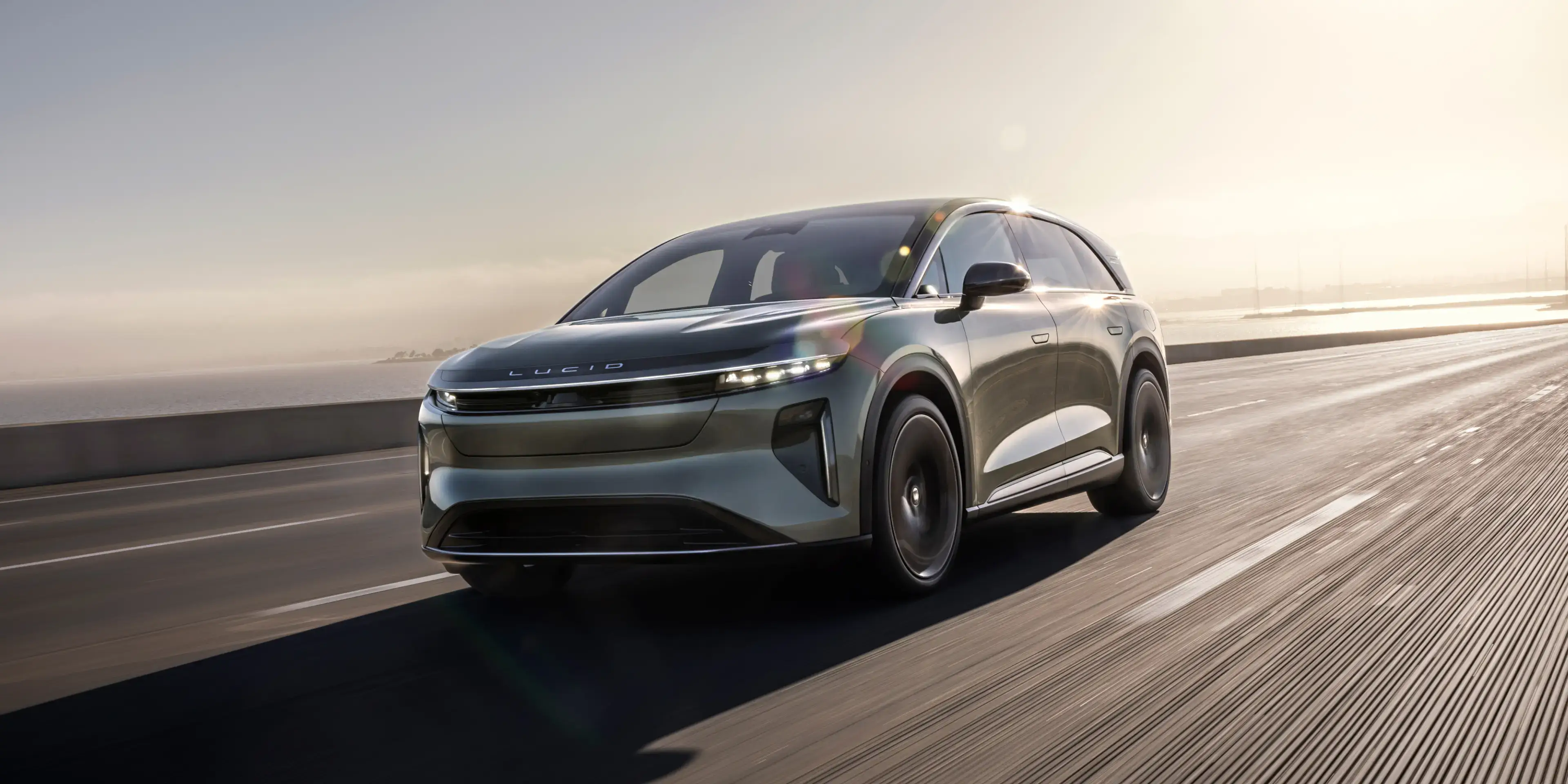 سيارة Lucid Gravity تسير على جسر فوق مسطح مائي في أجواء صافية.
