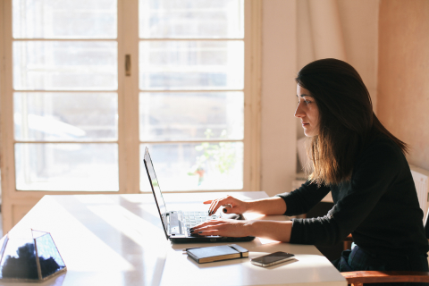 Woman seated at a desk typing on her laptop