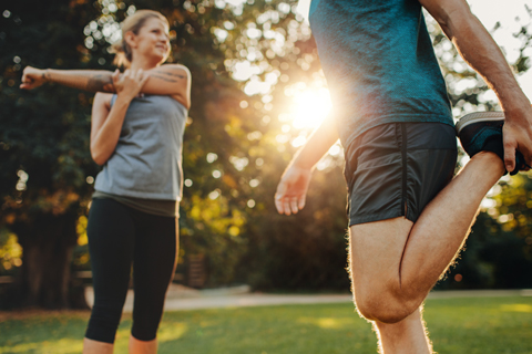 Two joggers stretching outside before a run.