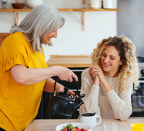 A stay at home mother pouring coffee and orange juice for her daughters.