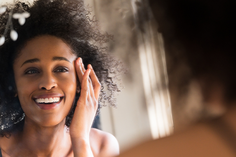 woman looking for signs of aging in the mirror