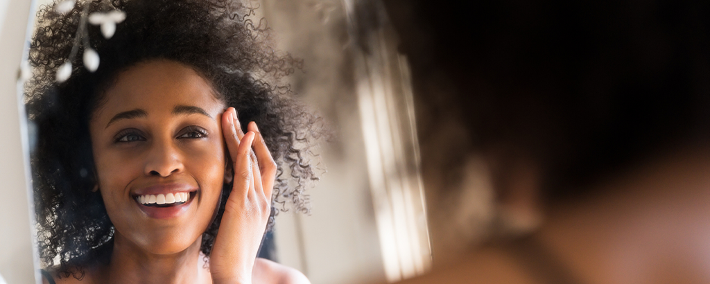 woman looking for signs of aging in the mirror