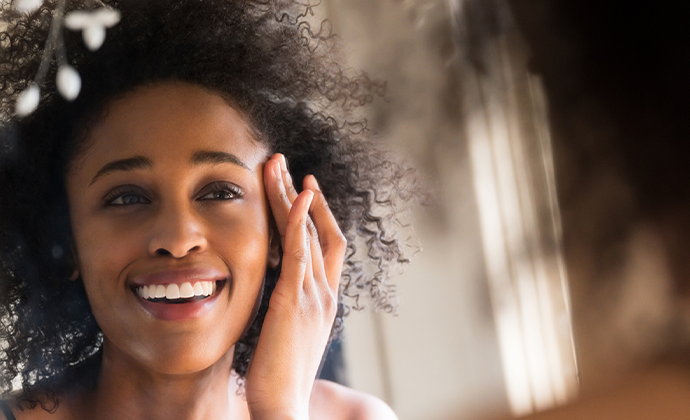 woman looking for signs of aging in the mirror