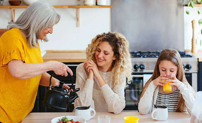 A stay at home mother pouring coffee and orange juice for her daughters.