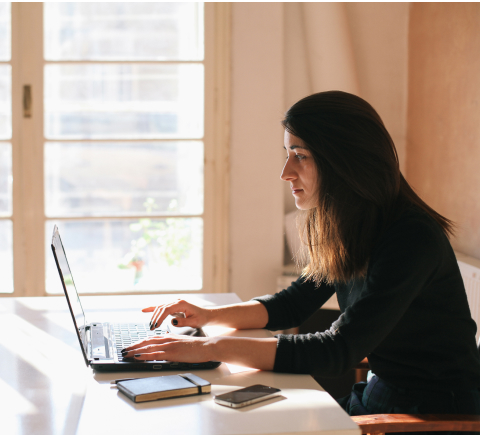 Woman seated at a desk typing on her laptop 