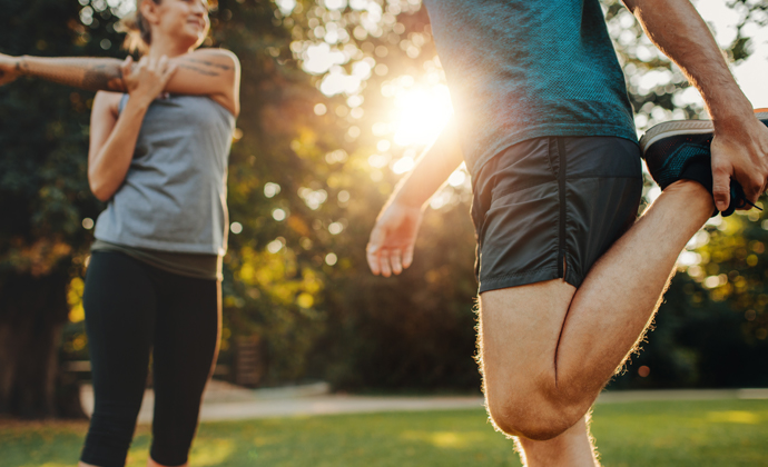 Two joggers stretching outside before a run.