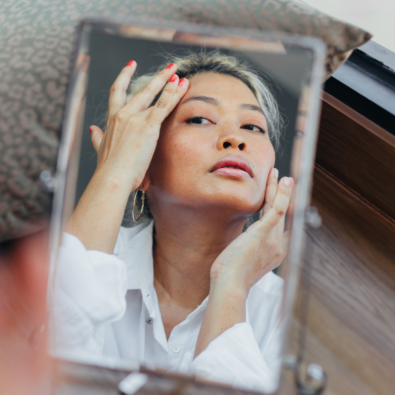 woman looking at the mirror for wrinkles