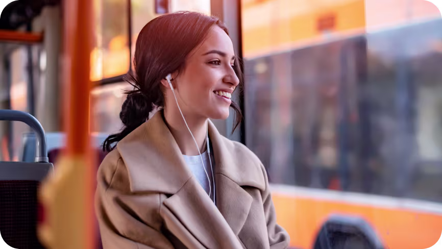 Woman on a bus with headphones in, looking out the window
