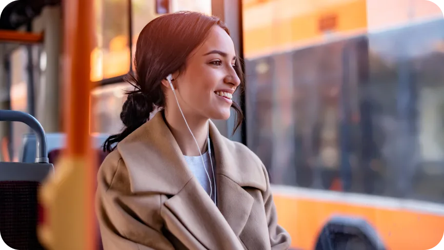 Woman on a bus with headphones in, looking out the window