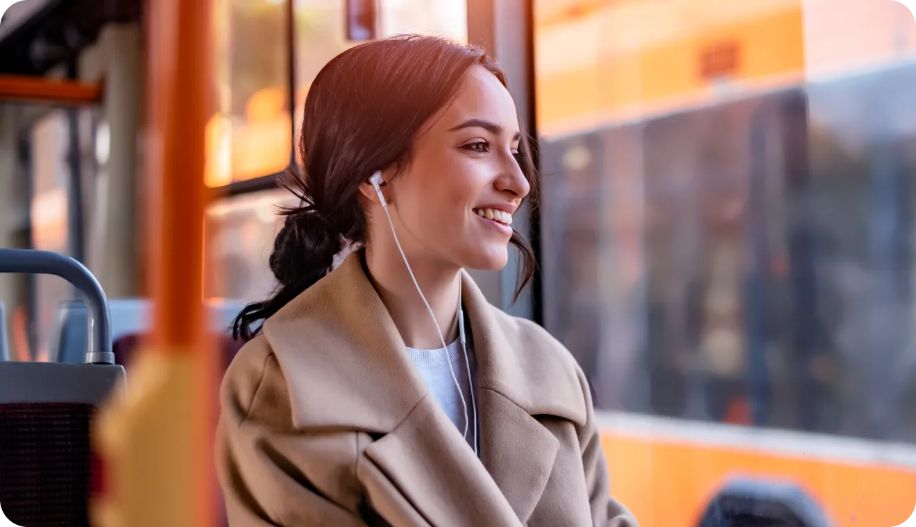 Woman on a bus with headphones in, looking out the window