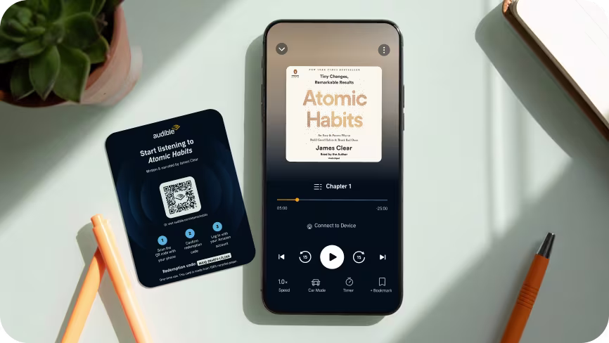Atomic Habits audiobook player showing on a phone screen with office material around