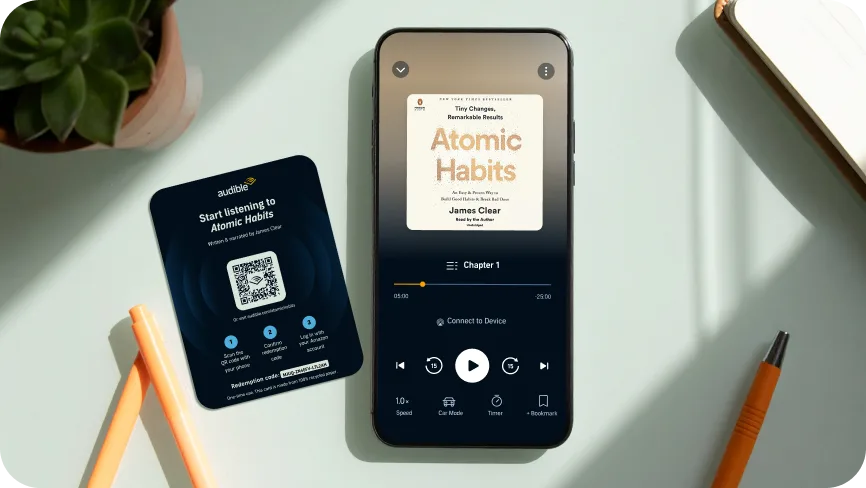 Atomic Habits audiobook player showing on a phone screen with office material around