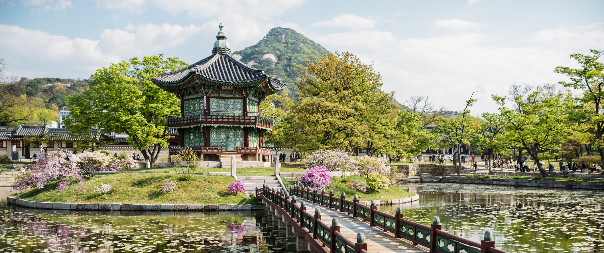 Corea del Sud - pagoda tipica su in isola all'interno di un lago, con un ponte antico che la collega alla terra ferma. Alberi e fiori tutti in torno al laghetto