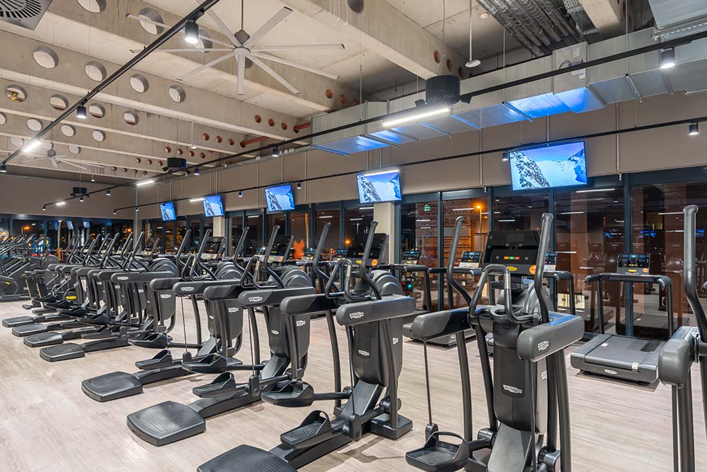 Offener Bereich für Ausdauertraining im FitX Fitnessstudio Augsburg-Lechhausen mit verschiedenen Cardio-Geräten. An den Wänden hängen Fernseher.