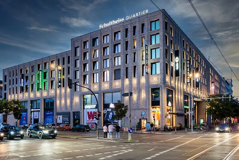 Bild: Außenansicht eines FitX Fitnessstudios. Ein großes FitX-Logo mit orangefarbenem X ist zu sehen. Das Gebäude befindet sich in einem urbanen Umfeld.
