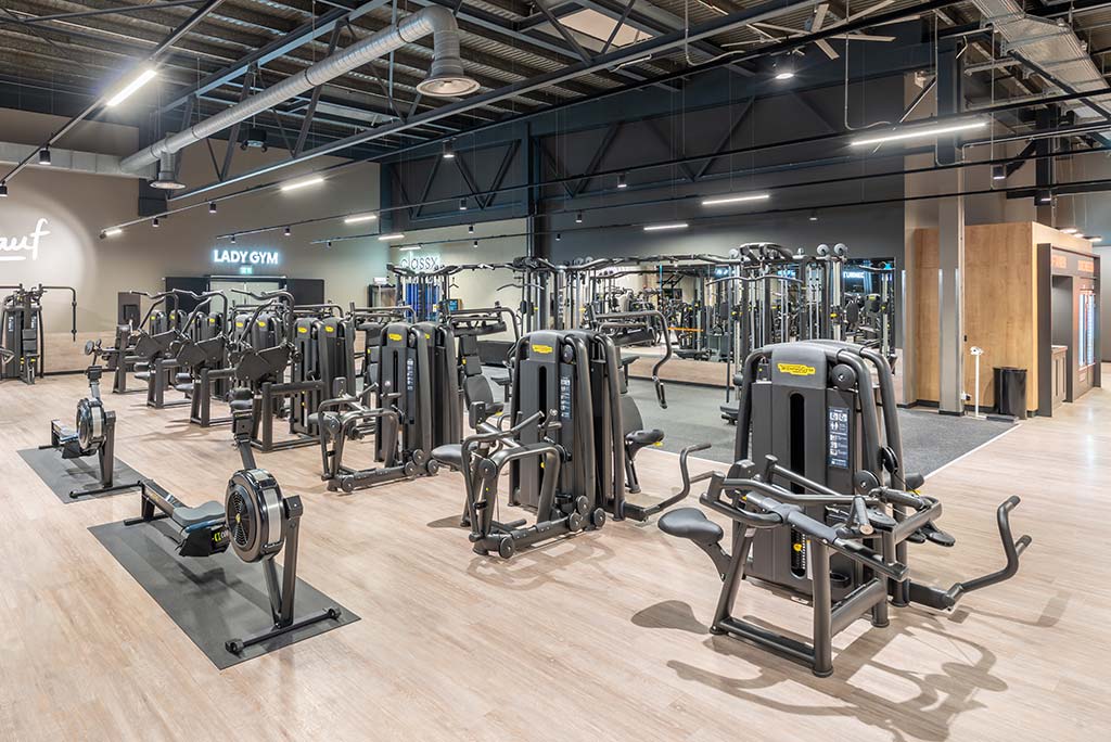 Gerätebereich im FitX Fitnessstudio Berlin-Ku'damm mit verschiedenen Kraftgeräten. Der Raum ist im industriellen Design gestaltet, mit offenen Deckenstrukturen und hellen Böden.