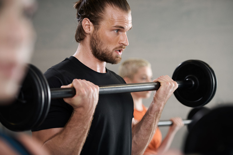 Bild: Teilnehmende im body-x-Kurs machen Bizeps-Curls mit einer Langhantel.