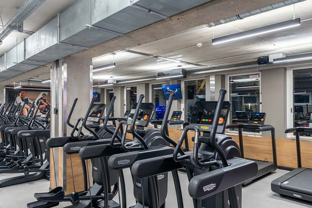 Offener Bereich für Ausdauertraining im FitX Fitnessstudio Düsseldorf-Derendorf mit verschiedenen Cardio-Geräten. An den Wänden hängen Fernseher.