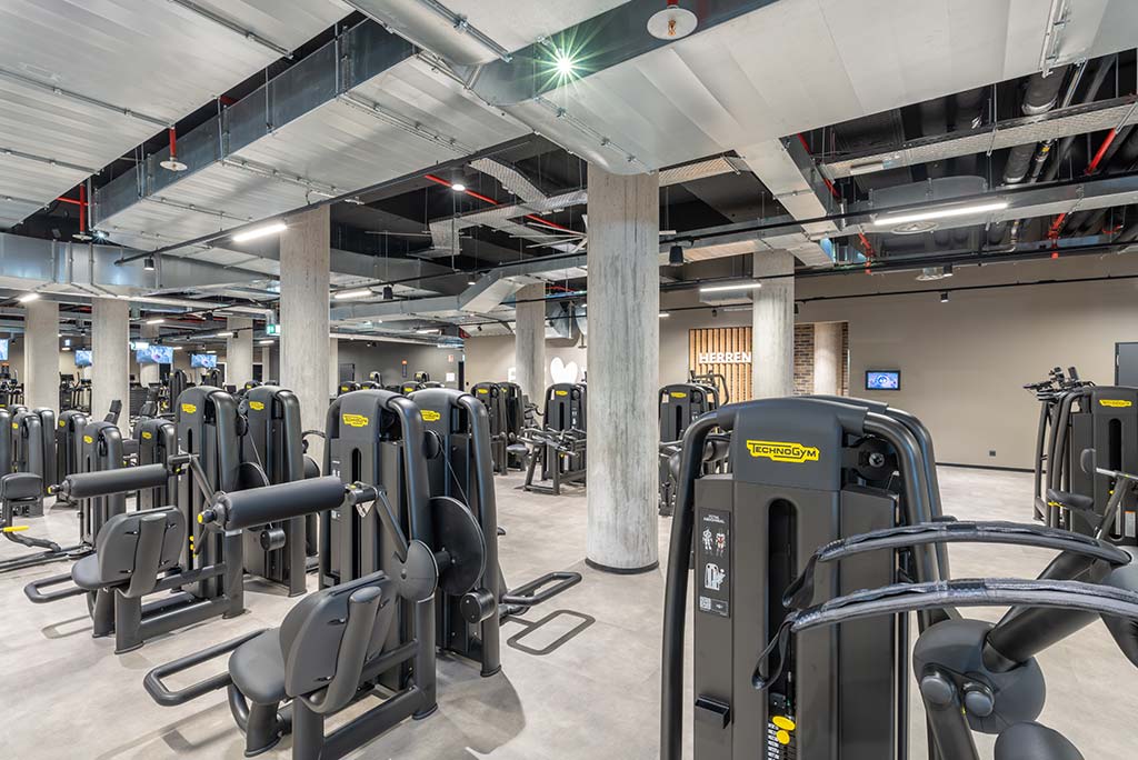 Gerätebereich im FitX Fitnessstudio Böblingen-Zentrum mit verschiedenen Kraftgeräten. Der Raum ist im industriellen Design gestaltet, mit offenen Deckenstrukturen und hellen Böden.