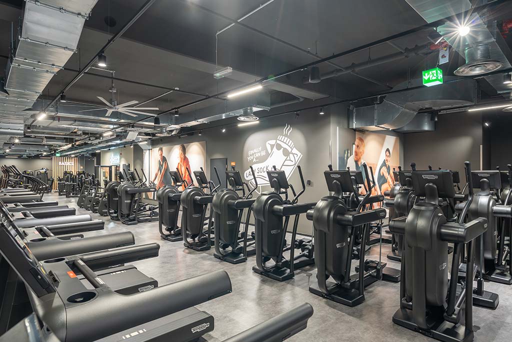 Offener Bereich für Ausdauertraining im FitX Fitnessstudio Aachen-Mitte mit verschiedenen Cardio-Geräten. An den Wänden hängen Fernseher.