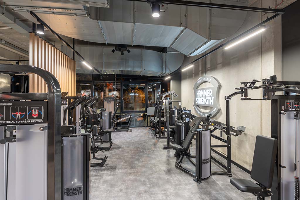 Zirkel-Bereich im FitX Fitnessstudio Remscheid-Süd, in dem verschiedene Trainingsgeräte kreisförmig angeordnet sind. Über den Geräten hängt ein großer Leuchtring, der in grün oder rot leuchtet und die Übungsdauer anzeigt.