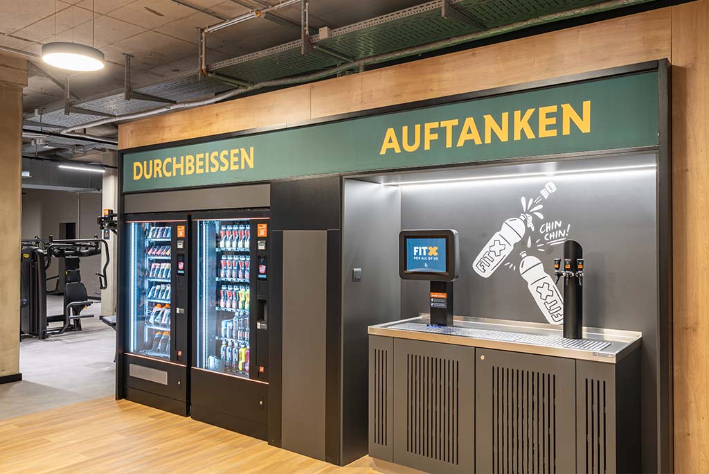 Abgetrennter Lounge-Bereich im FitX Fitnessstudio Essen-Bergerhausen mit verschiedenen Sitzmöglichkeiten. Der Bereich ist hell, freundlich und im industriellen Design gestaltet.