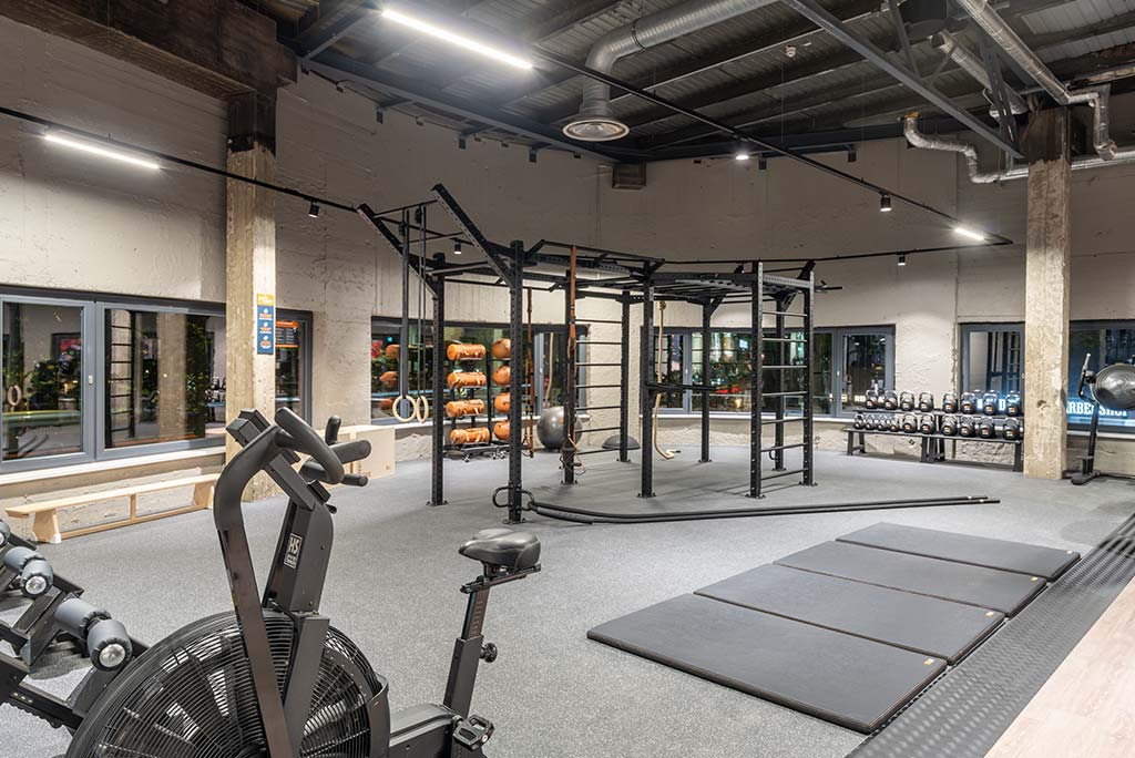 Spezielle Turnecke im FitX Fitnessstudio Berlin-Ku'damm. Im Zentrum steht ein großes Turngerät mit Sprossenleitern, Ringen, Battle-Ropes und Hangelmöglichkeiten. An der Seite befinden sich Medizinbälle, Kettlebells sowie Plyo-Boxen aus Holz.