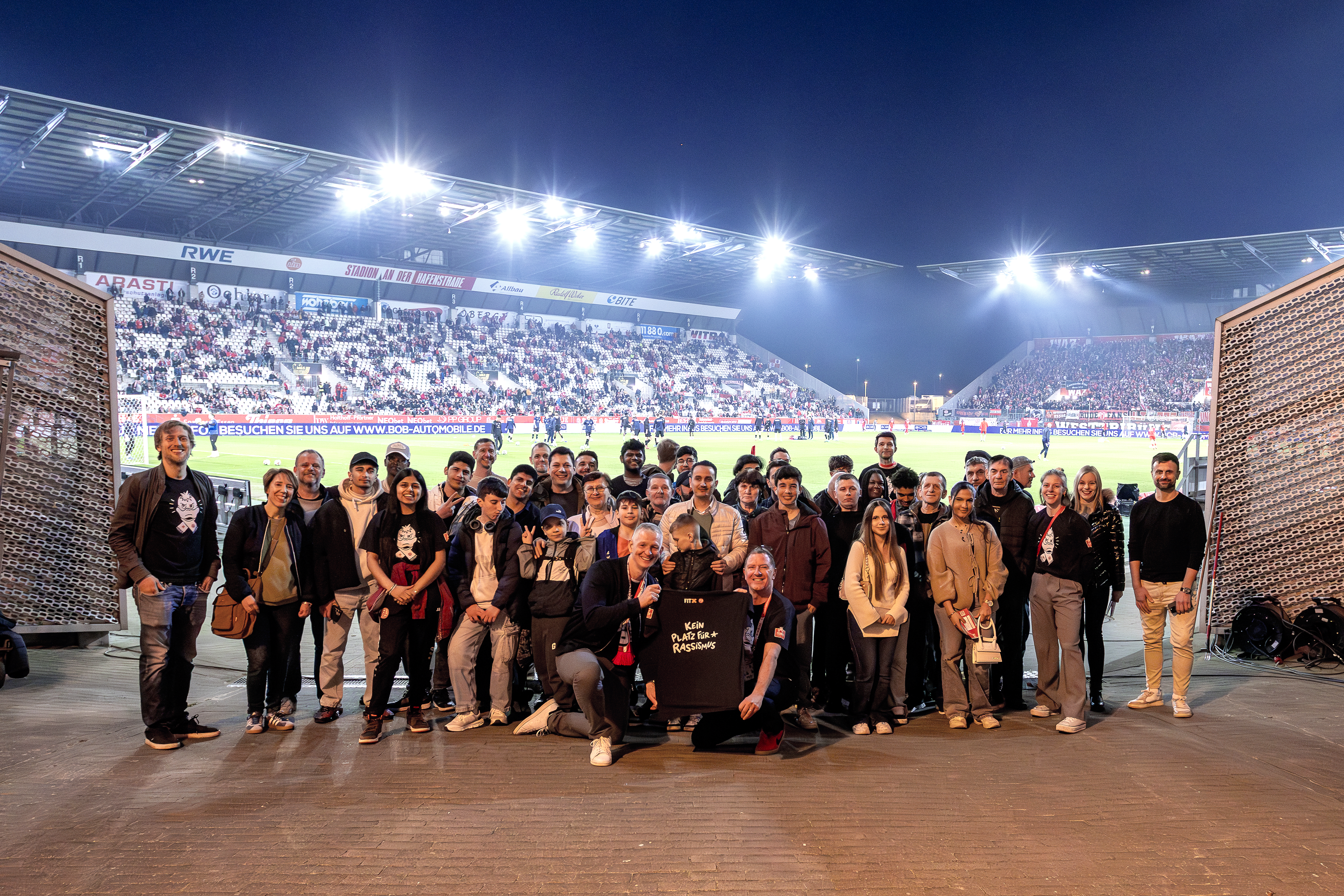 Bild: Gruppenbild der eingeladenen Geflüchteten sowie der Schülerinnen und Schüler der Alfred-Krupp Schule und des Gymnasiums Essen-Überruhr im RWE Stadion.