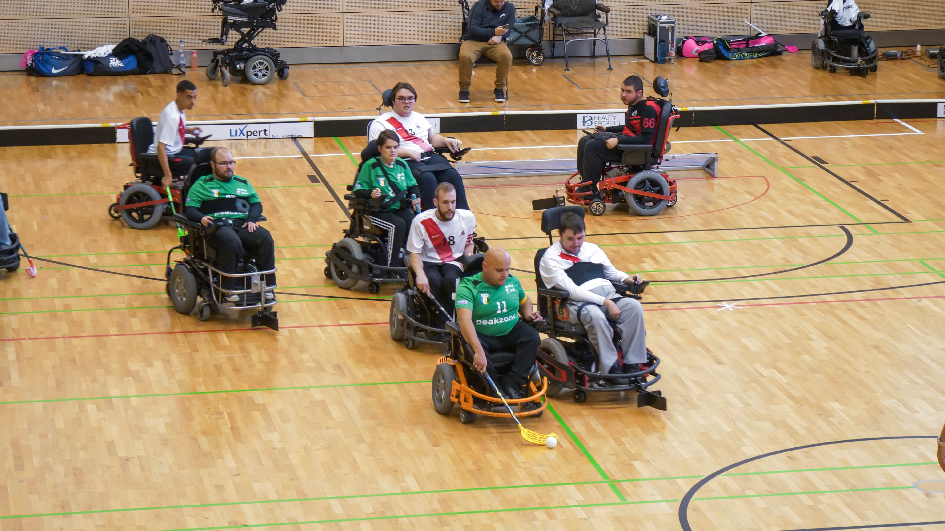 Bild: Eine Gruppe von Menschen, die in Rollstühlen sitzt, spielt Hockey.