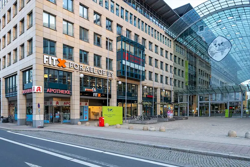 Bild: Außenansicht eines FitX Fitnessstudios. Ein großes FitX-Logo mit orangefarbenem X ist zu sehen. Das Gebäude befindet sich in einem urbanen Umfeld.