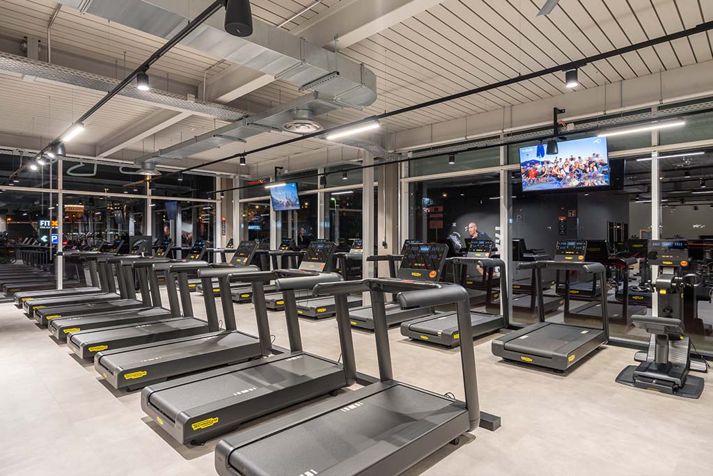 Offener Bereich für Ausdauertraining im FitX Fitnessstudio Wuppertal-Elberfeld mit verschiedenen Cardio-Geräten. An den Wänden hängen Fernseher.