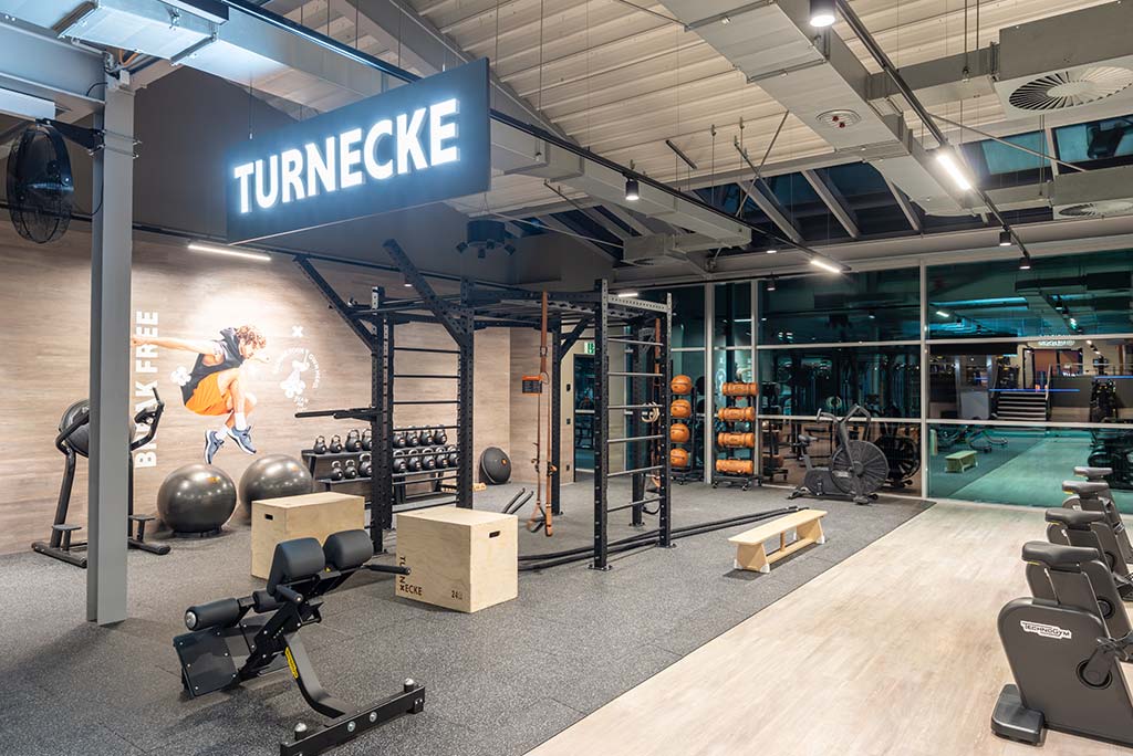Spezielle Turnecke im FitX Fitnessstudio Neuss-Innenstadt. Im Zentrum steht ein großes Turngerät mit Sprossenleitern, Ringen, Battle-Ropes und Hangelmöglichkeiten. An der Seite befinden sich Medizinbälle, Kettlebells sowie Plyo-Boxen aus Holz.