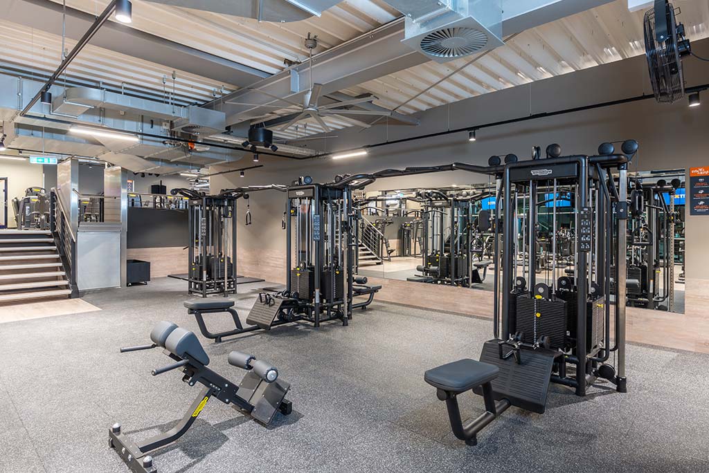 Gerätebereich im FitX Fitnessstudio Neuss-Innenstadt mit verschiedenen Kraftgeräten. Der Raum ist im industriellen Design gestaltet, mit offenen Deckenstrukturen und hellen Böden.