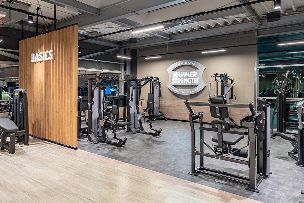 Zirkel-Bereich im FitX Fitnessstudio Neuss-Innenstadt, in dem verschiedene Trainingsgeräte kreisförmig angeordnet sind. Über den Geräten hängt ein großer Leuchtring, der in grün oder rot leuchtet und die Übungsdauer anzeigt.
