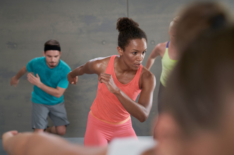 Bild: Teilnehmende im fatburn-x-Kurs machen eine dynamische Ausdauerbewegung.
