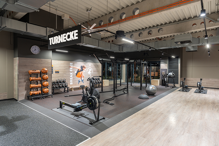 Abgetrennter Lounge-Bereich im FitX Fitnessstudio Augsburg-Lechhausen mit verschiedenen Sitzmöglichkeiten. Der Bereich ist hell, freundlich und im industriellen Design gestaltet.