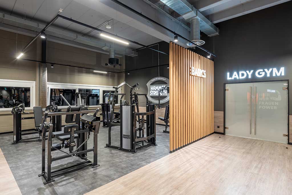 Zirkel-Bereich im FitX Fitnessstudio Nürnberg-Zabo, in dem verschiedene Trainingsgeräte kreisförmig angeordnet sind. Über den Geräten hängt ein großer Leuchtring, der in grün oder rot leuchtet und die Übungsdauer anzeigt.