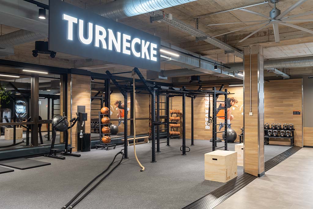 Spezielle Turnecke im FitX Fitnessstudio Essen-Bergerhausen. Im Zentrum steht ein großes Turngerät mit Sprossenleitern, Ringen, Battle-Ropes und Hangelmöglichkeiten. An der Seite befinden sich Medizinbälle, Kettlebells sowie Plyo-Boxen aus Holz.