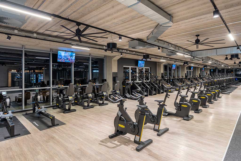 Offener Bereich für Ausdauertraining im FitX Fitnessstudio Leipzig-Neulindenau mit verschiedenen Cardio-Geräten. An den Wänden hängen Fernseher.
